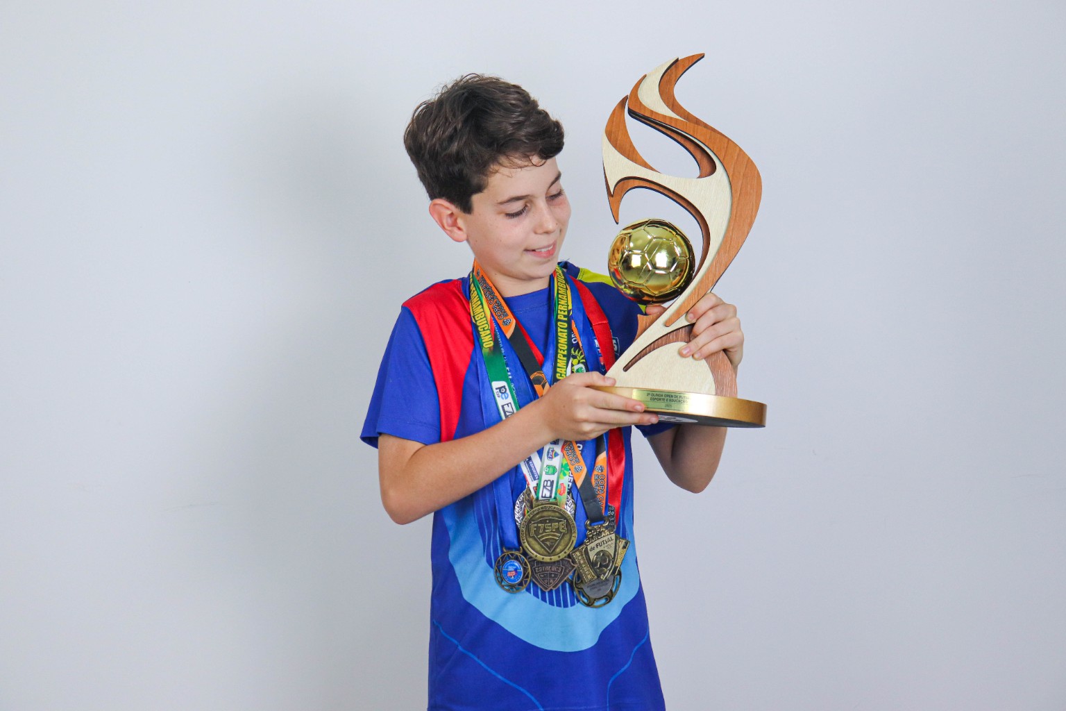 Estudante dos Anos Finais com troféu e medalhas do Colégio EXIMIUS